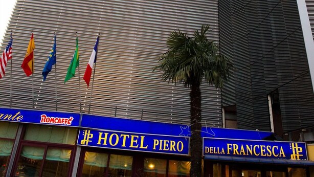 Un hotel moderno con fachada de vidrio curva, banderas y señalización que indica
