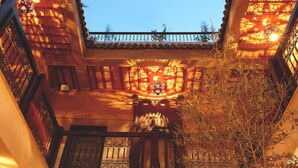 A wooden staircase with wrought iron railings leading to a balcony with a tiled roof. - Hotel Riad Carina (Marrakech)
