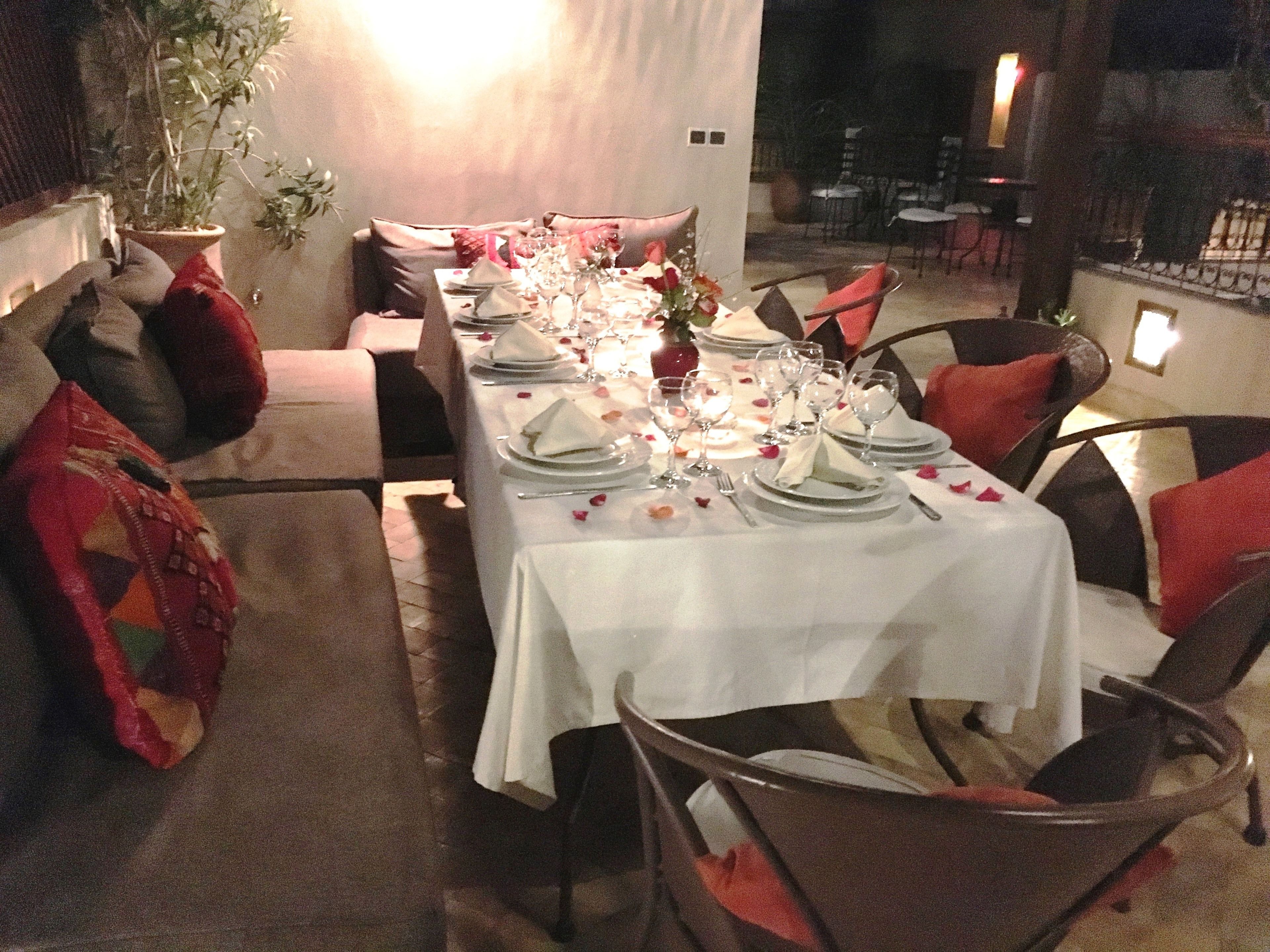A long dining table set for a meal with white tablecloths, plates, and glasses.