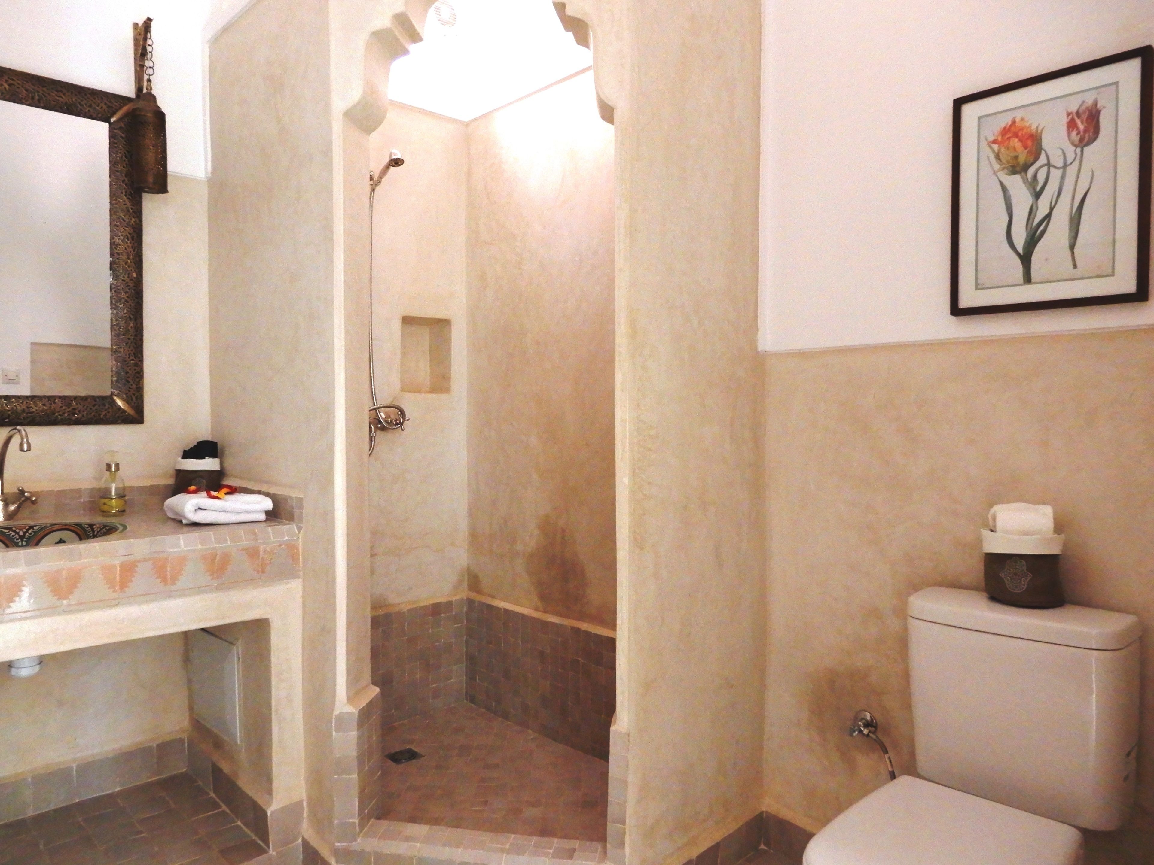 A bathroom with a shower, toilet, sink, and a framed picture on the wall.