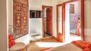 A room with a bed, a bench, and a door leading to another room. - Hotel Riad Carina (Marrakech)