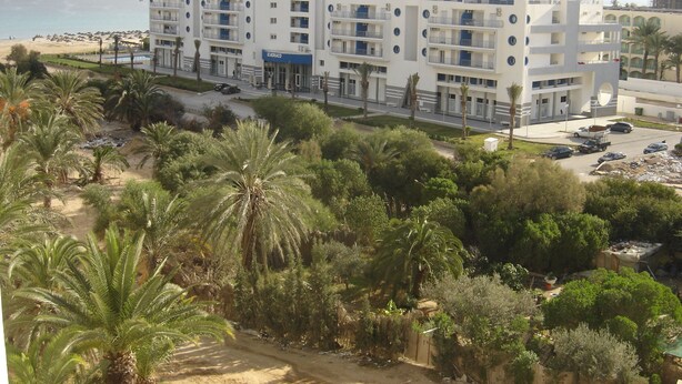 Un hotel de varios pisos con balcones, situado cerca de una playa.