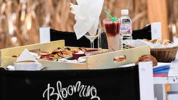 Un tavolo imbandito con cibo e bevande, un cesto di pane e un cartello con su scritto 'Blooming'.
