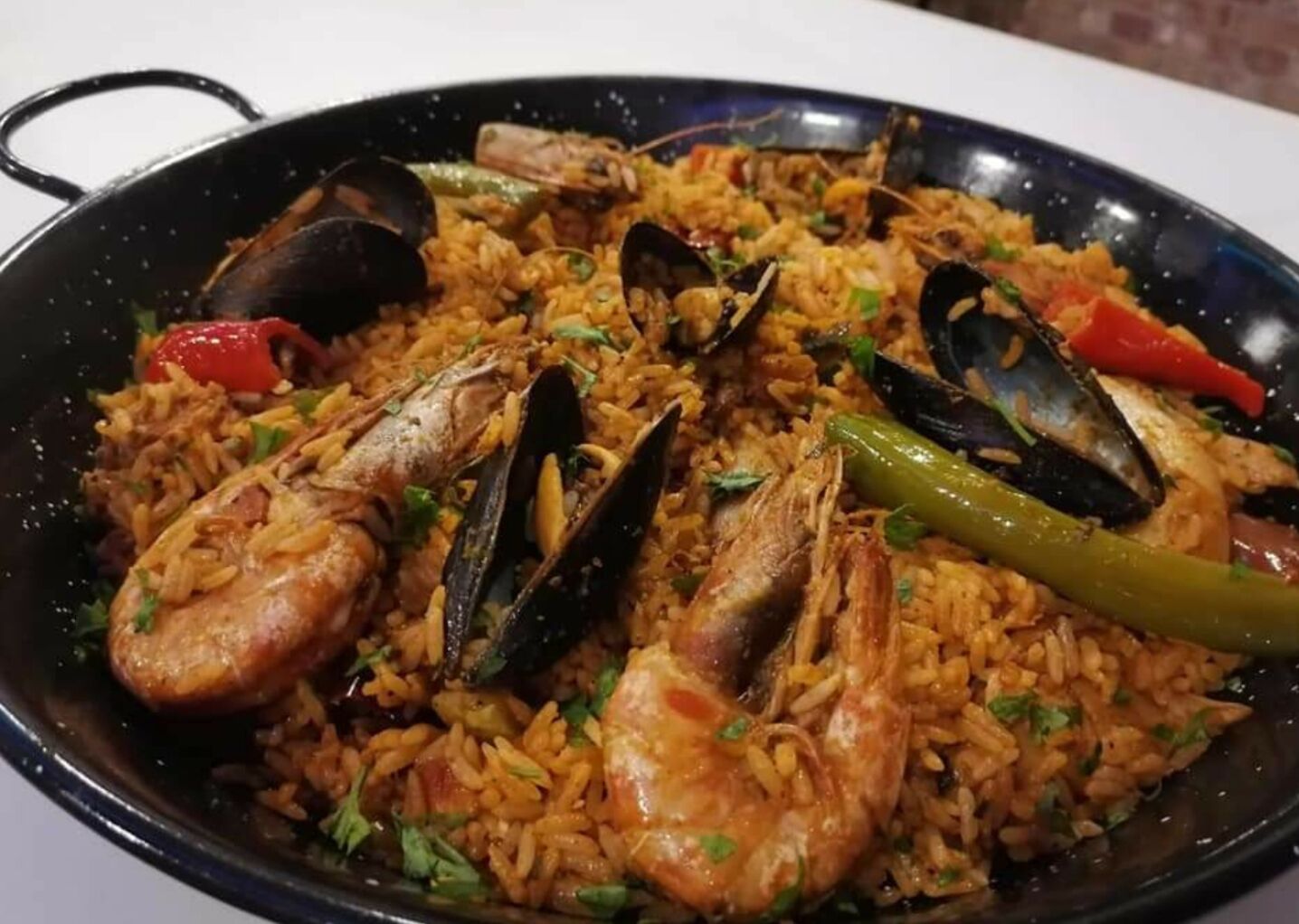 Paella mit Meeresfrüchten in einer schwarzen Pfanne.