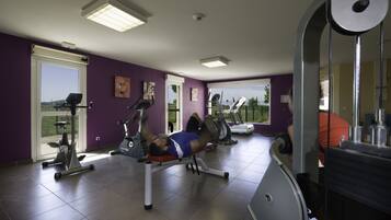 Un gimnasio con equipo de ejercicio, un ventanal grande y una pared morada.