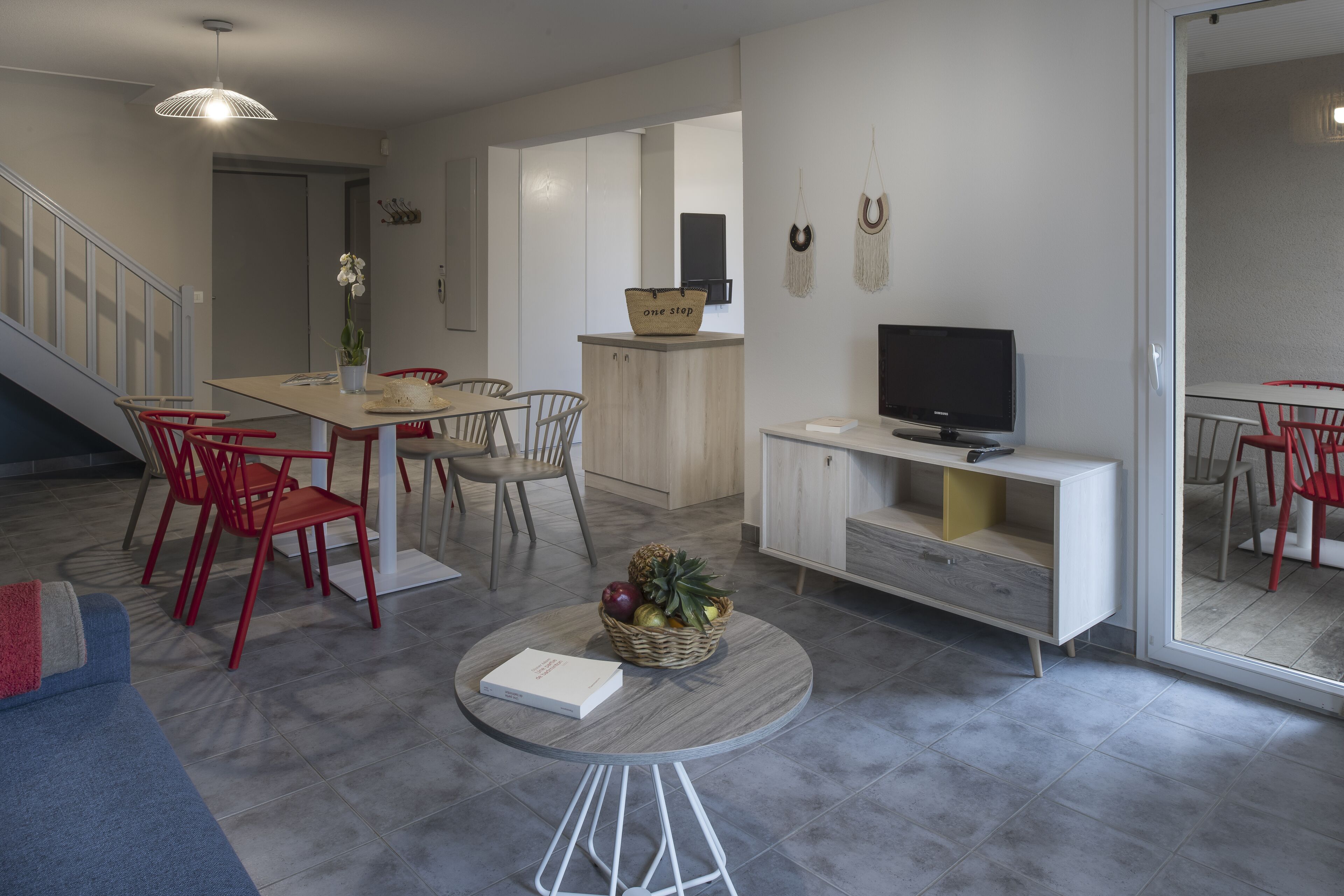 Un salon moderne comprenant un coin repas, un téléviseur et un escalier.