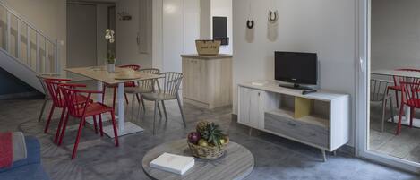 Un salon moderne comprenant un coin repas, un téléviseur et un escalier.