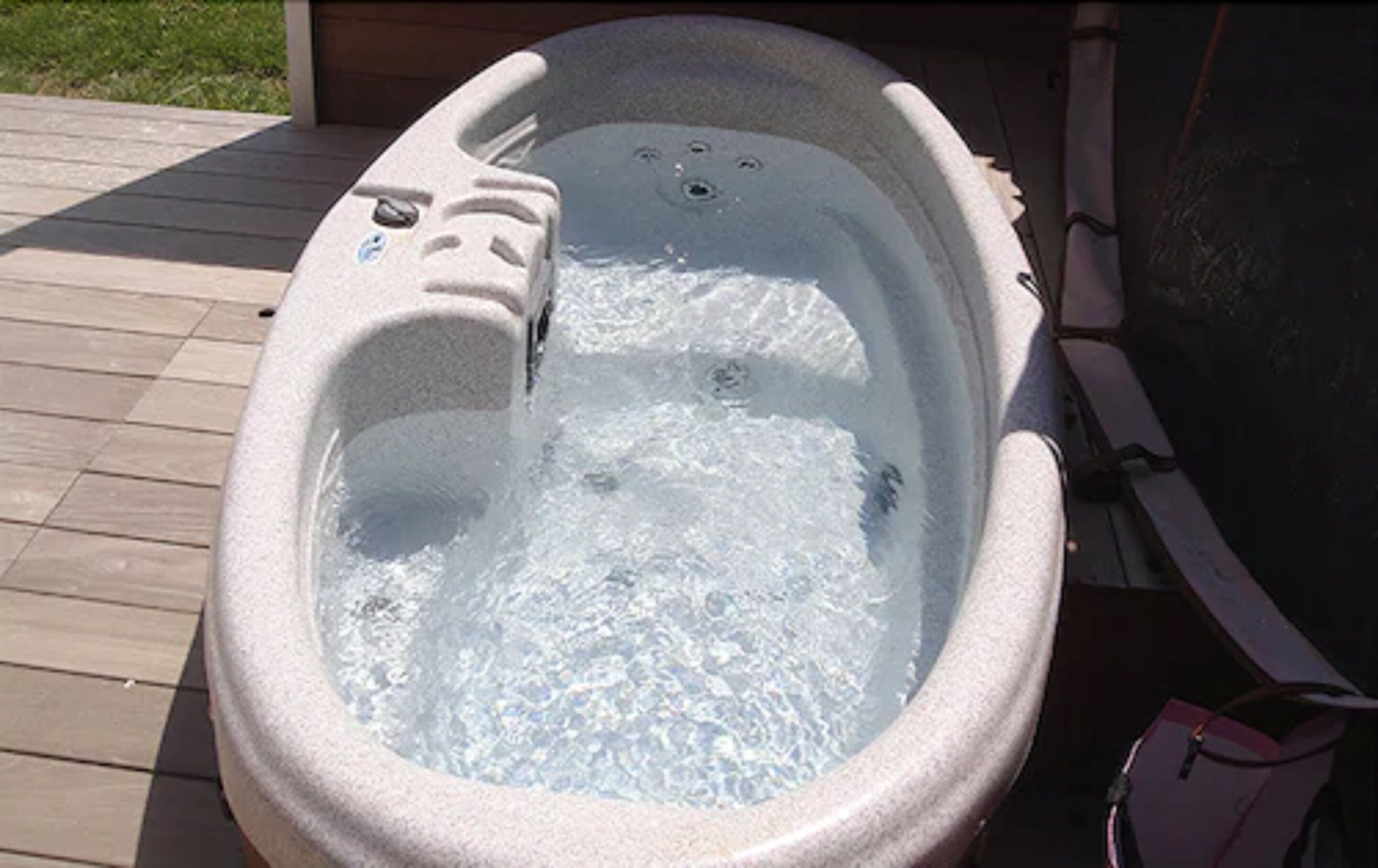 Un jacuzzi con chorros, rodeado por una terraza de madera.