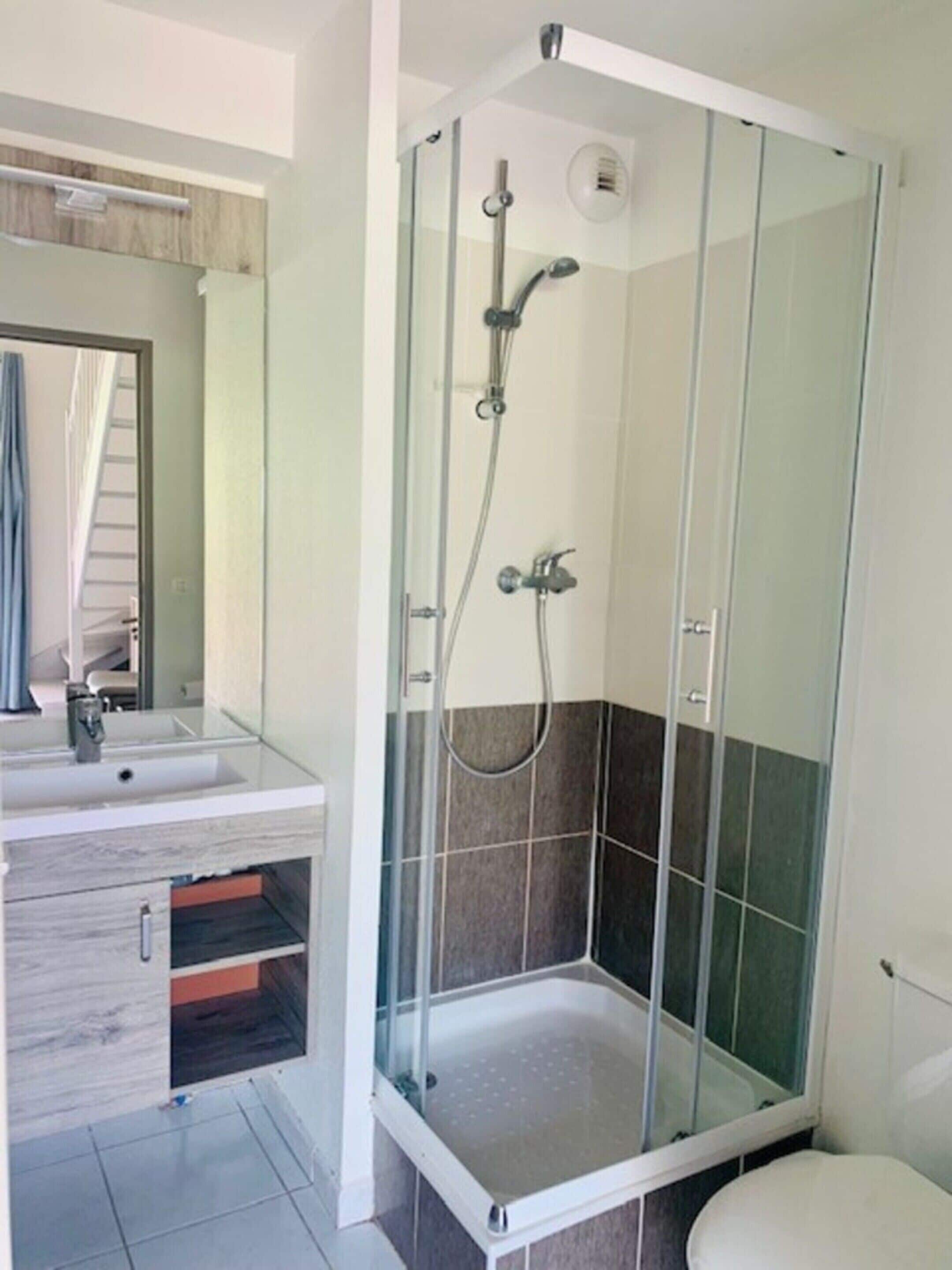 A modern bathroom with a glass-enclosed shower, a sink with a mirror, and a toilet.