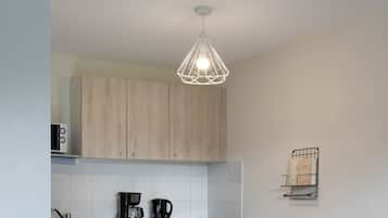 Una cocina moderna con armarios de madera, lavavajillas y un comedor con sillas rojas.