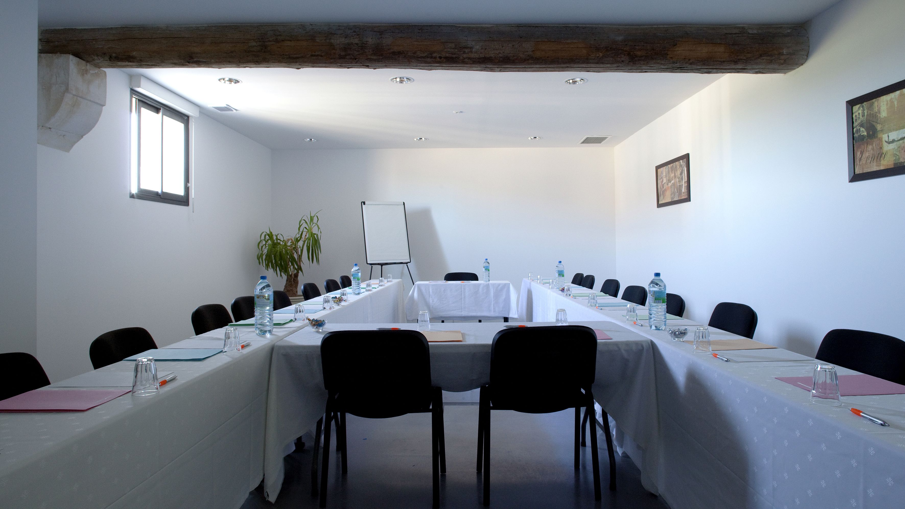Ett konferensrum med ett långt bord, stolar, vattenflaskor och en whiteboard.