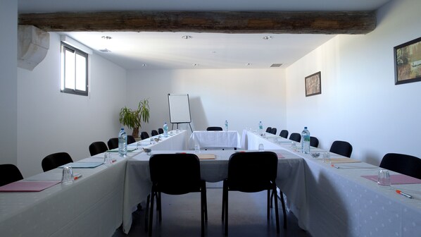 A conference room with a long table, chairs, water bottles, and a whiteboard.