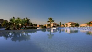 Una piscina cristalina rodeada de palmeras y edificios.