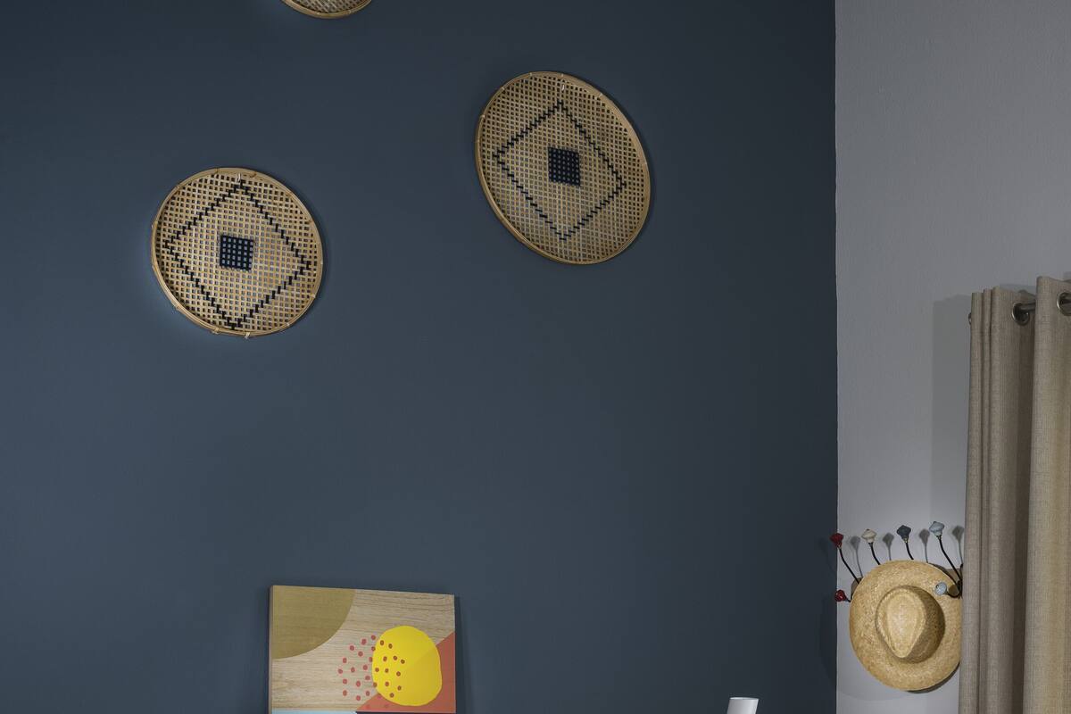 Una habitación moderna con un sofá azul oscuro, una mesa de centro redonda con libros, un cabecero de madera y decoración mural.