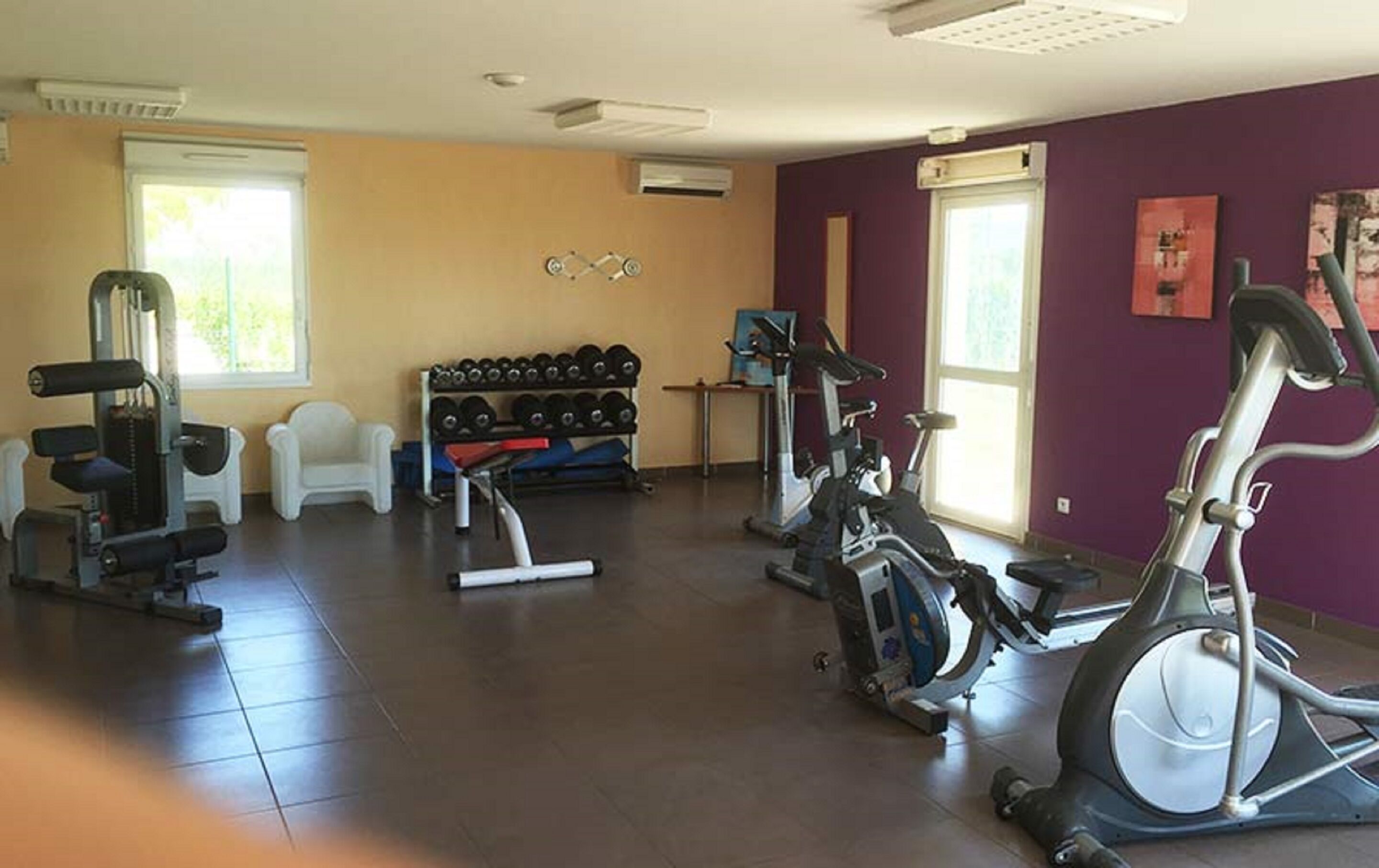A gym with exercise equipment, a bench, dumbbells, and a treadmill.