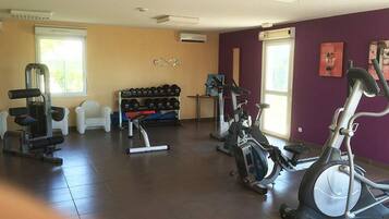 A gym with exercise equipment, a bench, dumbbells, and a treadmill.