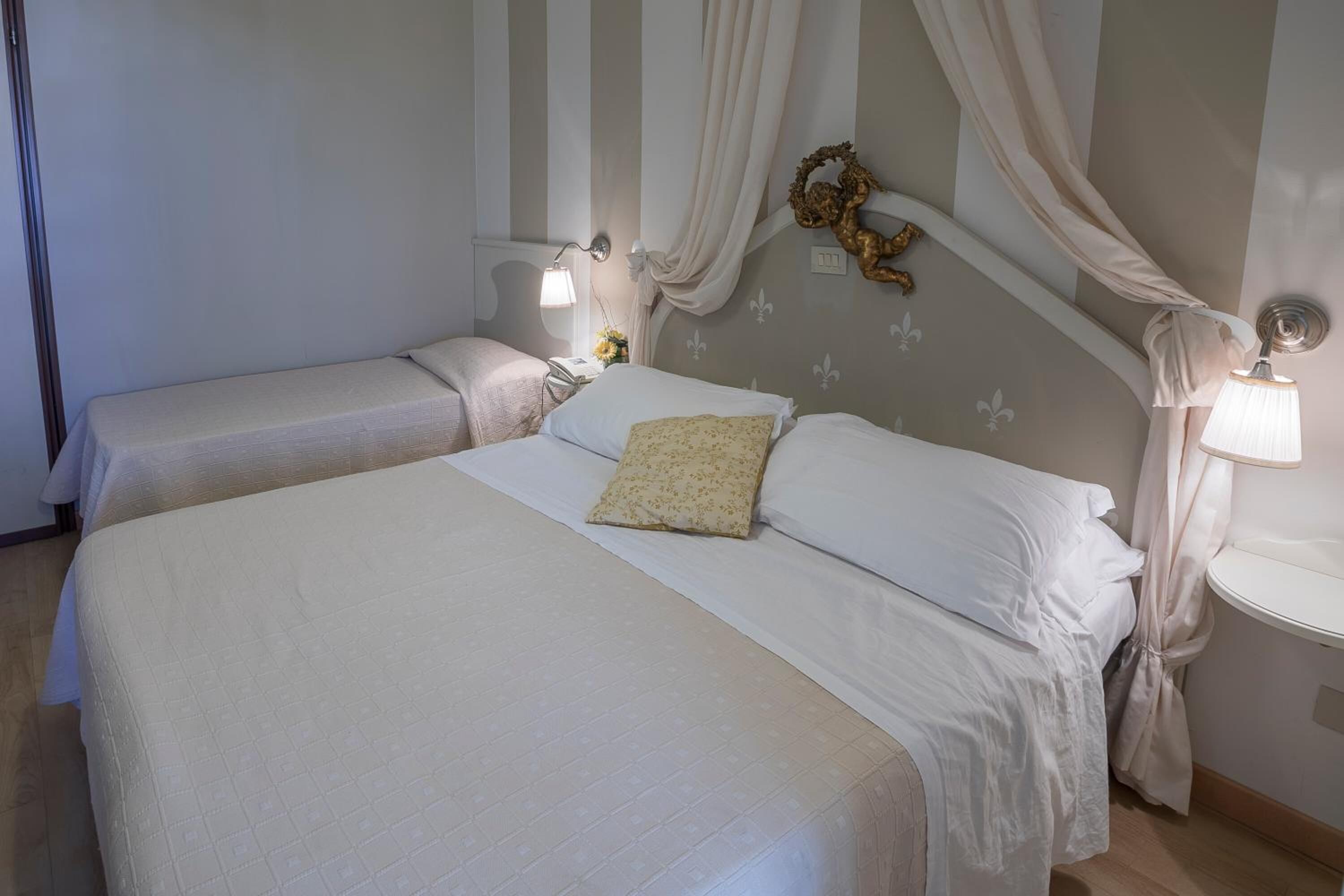 Una habitación de hotel con dos camas, cada una con una mesita de noche y lámpara. La habitación presenta un diseño de pared a rayas y un adorno decorativo sobre las camas.