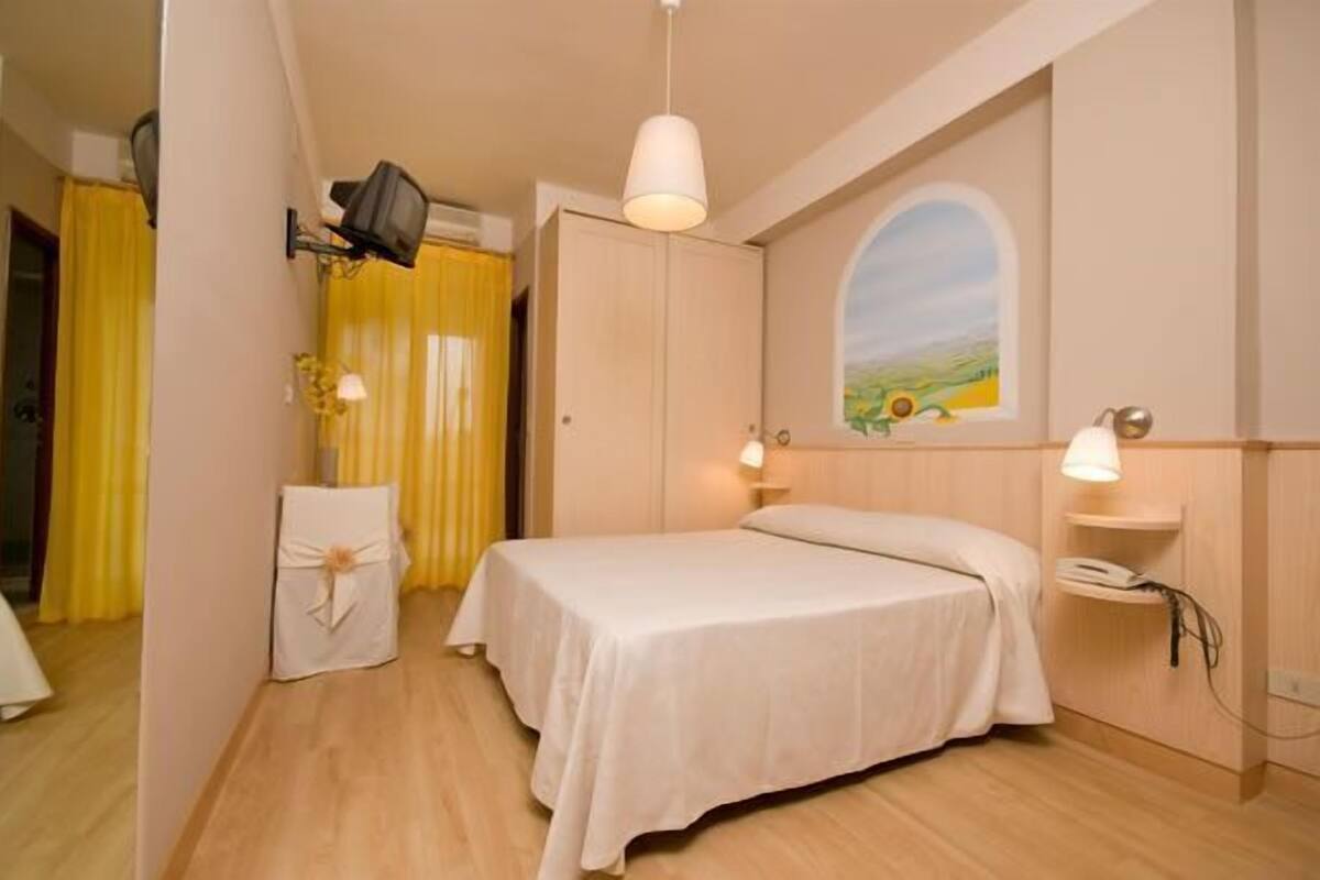 Ein Schlafzimmer mit einem Bett, einem Schreibtisch, einem Stuhl und einem Bild an der Wand.