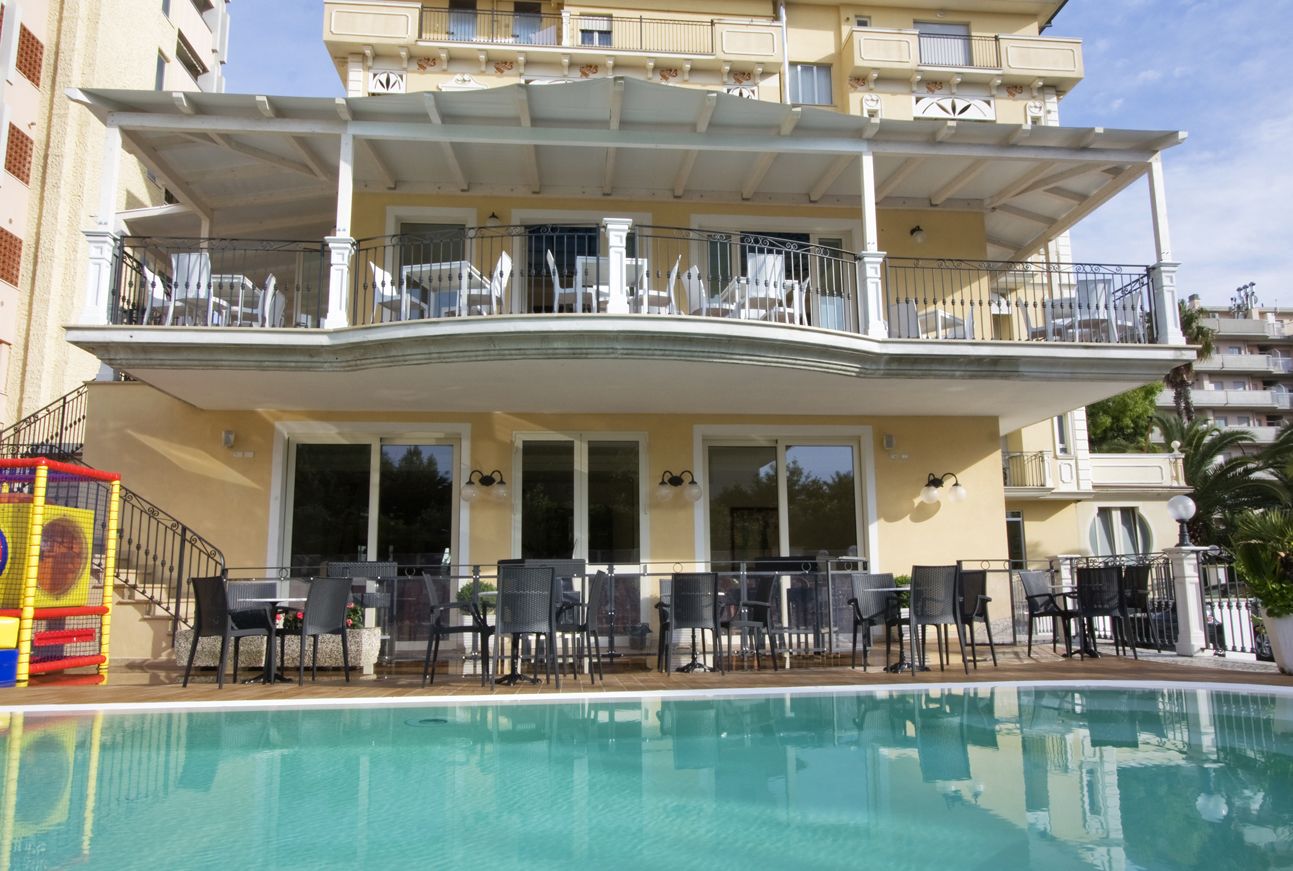 A hotel with a pool, outdoor seating, and balconies.