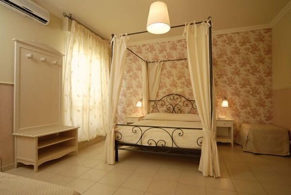 A four-poster bed with a canopy, a bedside table with a lamp, a wardrobe, and a small bench.