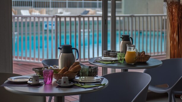 A breakfast setup with a table, chairs, and a view of a swimming pool.