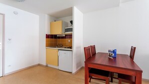 A compact kitchen with a microwave, sink, and cabinets, adjacent to a dining table with chairs.