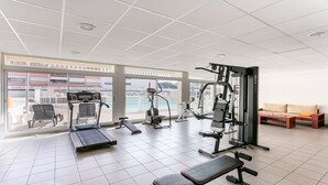 A gym with cardio machines, weight equipment, and a bench.