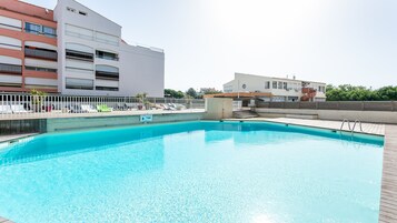 Une piscine rectangulaire avec une terrasse en bois, entourée d’une clôture blanche.