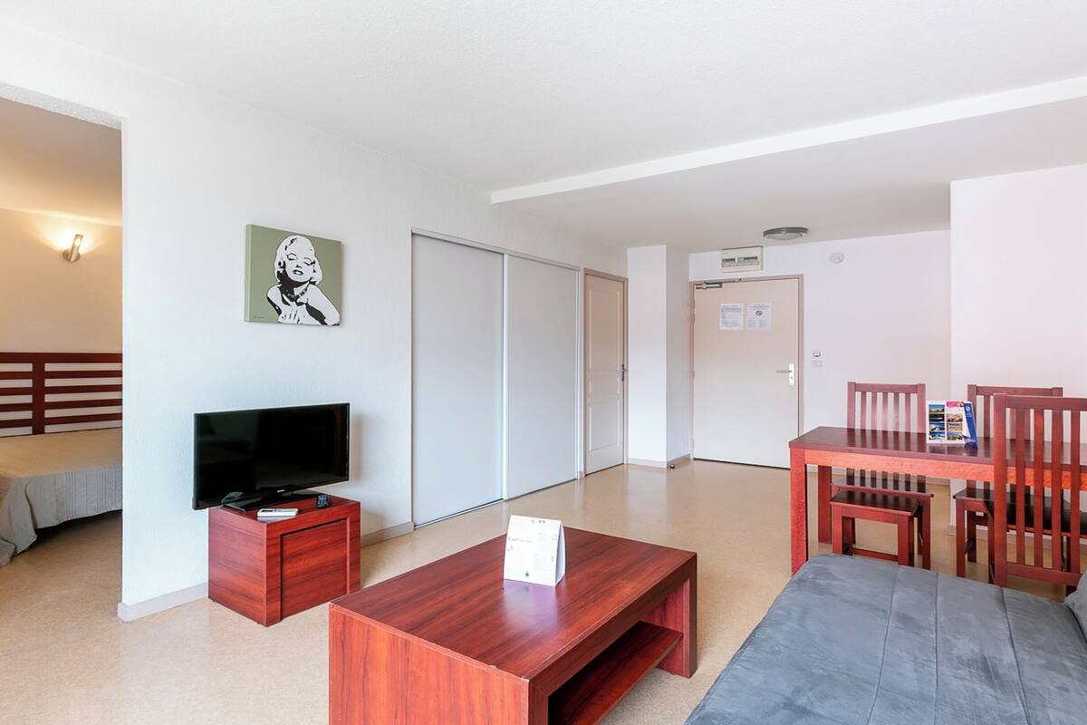 Une chambre d’hôtel équipée d’un lit, d’une télévision, d’un bureau, d’une chaise et d’un canapé.