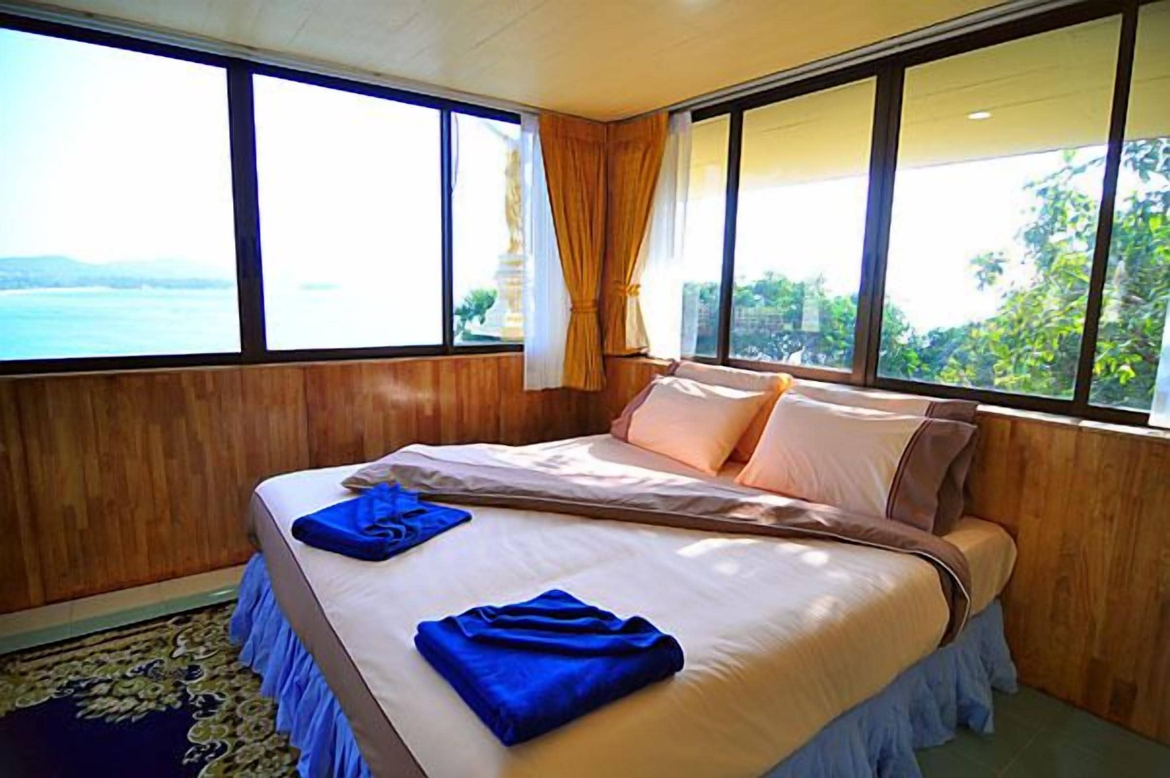 Un dormitorio con una cama grande, paredes de madera y vista al mar.