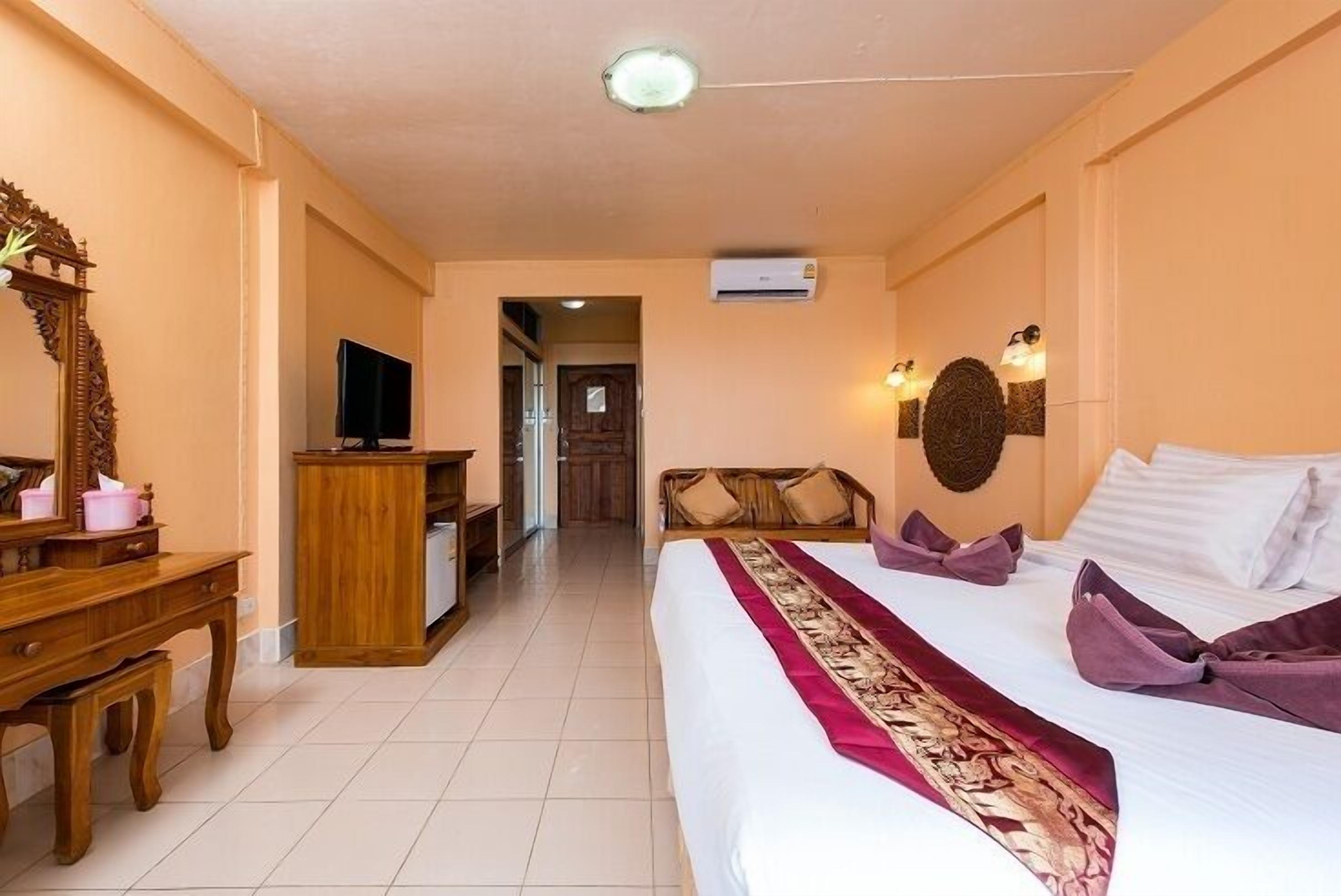 A hotel room with a bed, a desk, a television, and a mirror.