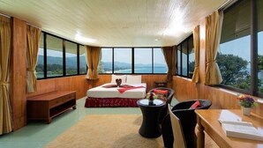 Un dormitorio con una cama grande, paredes de madera, techo de madera y vistas a las montañas.