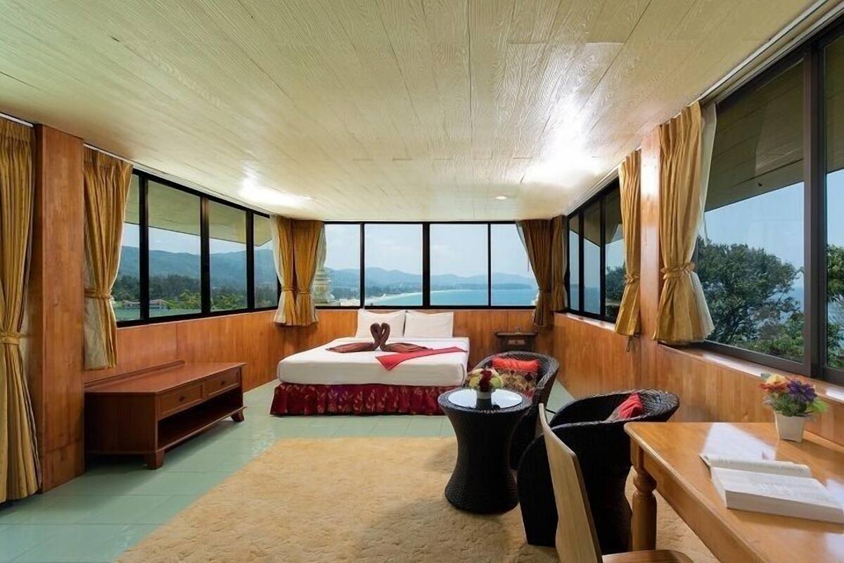 Un dormitorio con una cama grande, paredes de madera, techo de madera y vistas a las montañas.