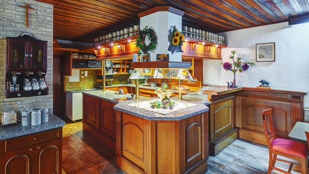 Una cocina con armarios de madera, una isla central con fregadero y una barra de desayuno. Hay elementos decorativos como un adorno y girasoles en la isla.
