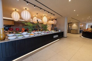 A buffet with various food items, overhead lighting, and a modern interior design.