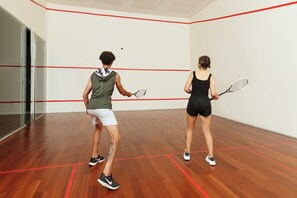 Ein Squashplatz mit Holzboden und roten Linien, die die Spielfeldmarkierungen zeigen.