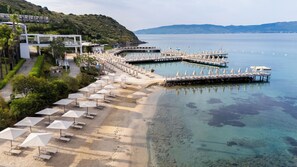 A beach resort with sun umbrellas, lounge chairs, a pier, and clear blue water. - Kefaluka Resort - All Inclusive (Bodrum)