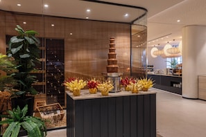 Un interior moderno con una exhibición central de objetos decorativos, una partición de vidrio y una zona de estar con mostrador.