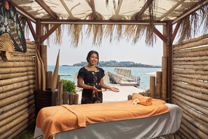 Ein Wellnessbereich mit Massageliege, Bambuswänden und Meerblick.