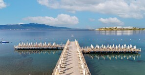A pier extending into calm waters with rows of sun loungers and umbrellas, a distant shoreline, and a clear sky. - Kefaluka Resort - All Inclusive (Bodrum)