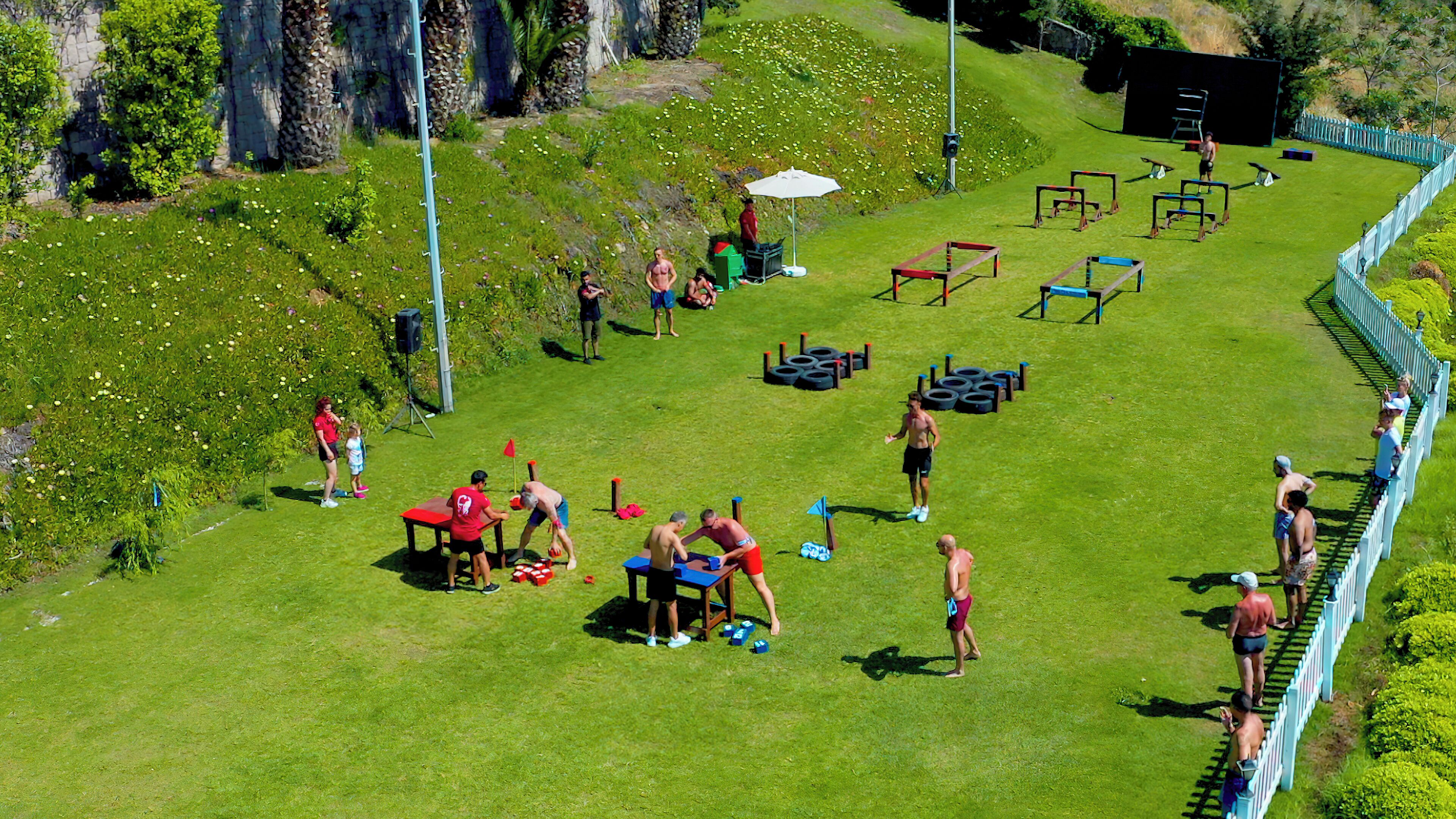 Espaço ao ar livre com gramado, equipamentos de ginástica e cerca delimitadora.