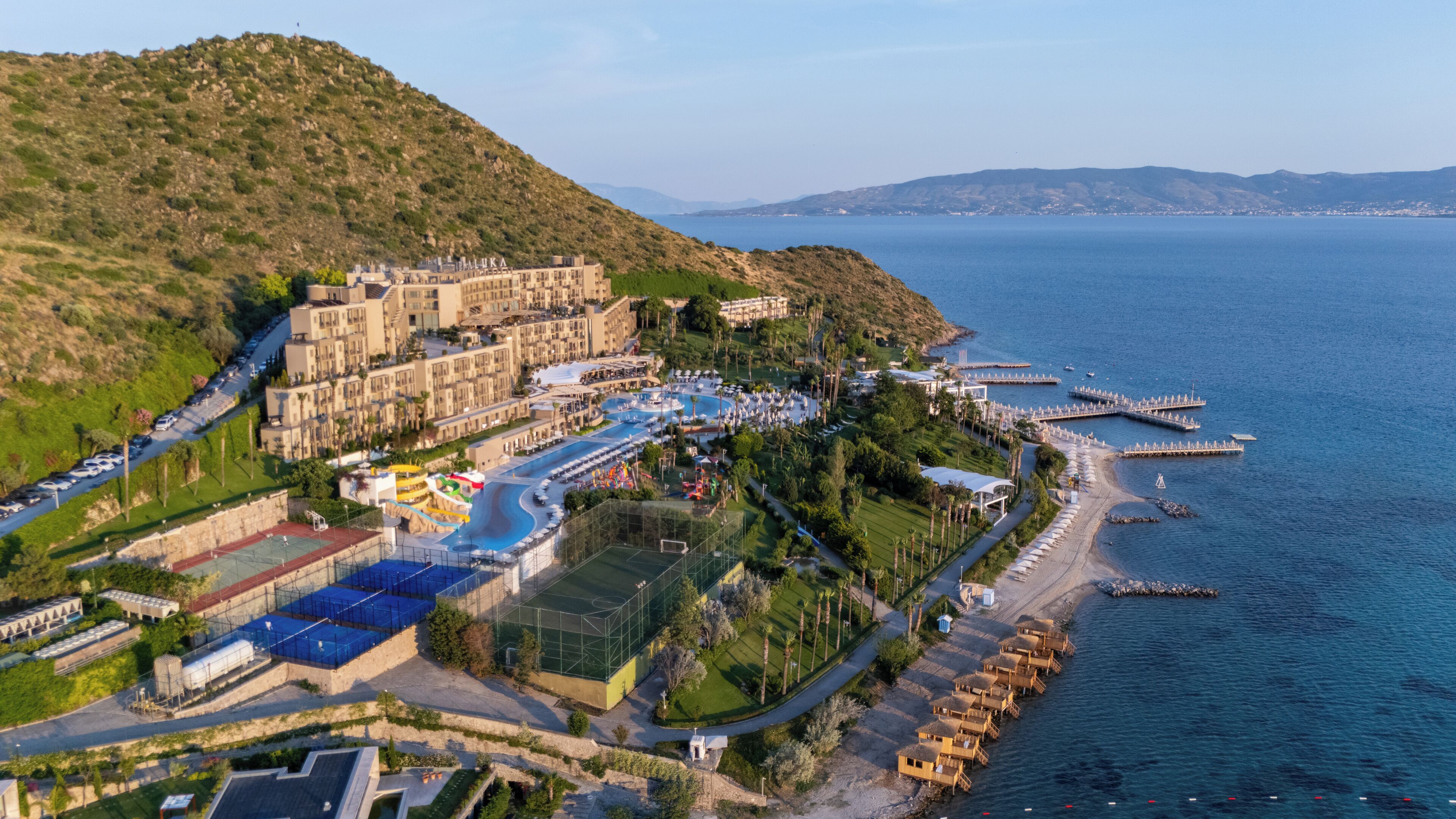 A resort with a large building, a swimming pool, and a beach area.