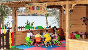 A wooden playhouse with a sign reading 'Zuzu House' and a view of a body of water. - Kefaluka Resort - All Inclusive (Bodrum)