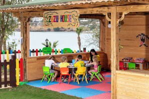 A wooden playhouse with a sign reading 'Zuzu House' and a view of a body of water. - Kefaluka Resort - All Inclusive (Bodrum)