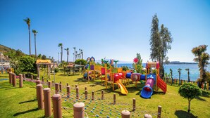 A playground with various play structures, a rope net, and a view of the sea. - Kefaluka Resort - All Inclusive (Bodrum)