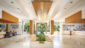 A spacious lobby with a central reception desk, framed artwork on the walls, and a large chandelier. - Kefaluka Resort - All Inclusive (Bodrum)