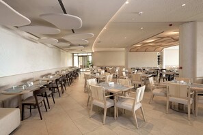 A spacious dining area with multiple tables and chairs, modern ceiling design, and large windows allowing natural light. - Kefaluka Resort - All Inclusive (Bodrum)