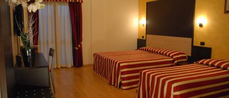 Habitación de hotel con dos camas, un escritorio y una silla.
