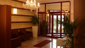 A lobby with a chandelier, a reception desk, and potted plants. - Iacone (Chieti)