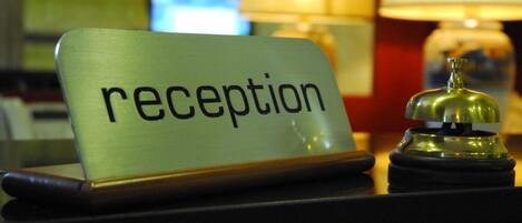A reception desk with a sign that reads "reception" and a bell.